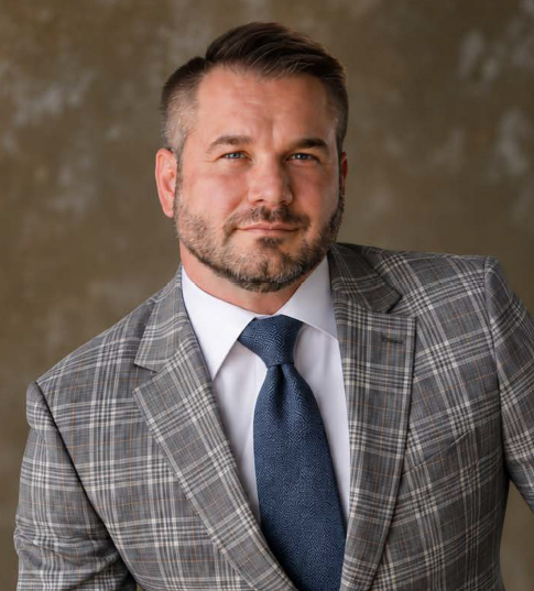 Brian Crockett wearing a gray checkered suit and blue tie